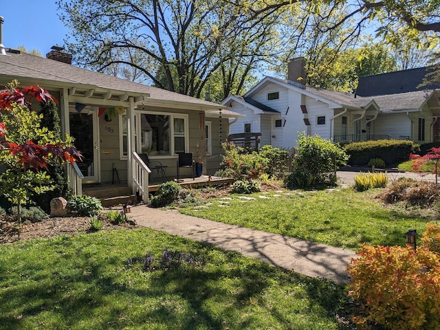 exterior space featuring covered porch, a chimney, and a front yard