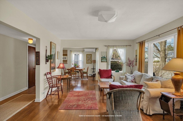 living area with baseboards, a wall mounted AC, wood finished floors, and visible vents