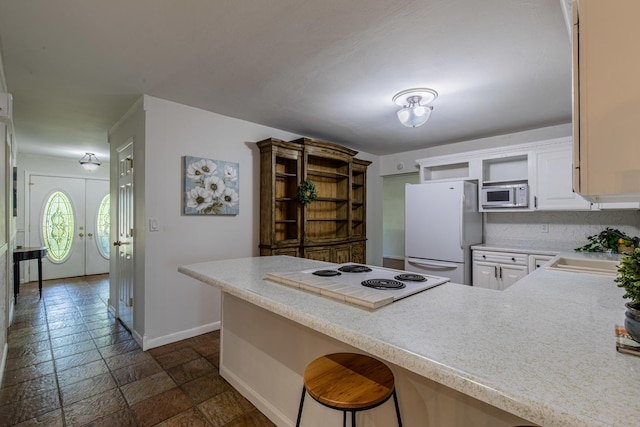 854 Kings Cv, Princeton, IL 61356 - kitchen featuring white appliances, a sink, a peninsula, baseboards, and light countertops