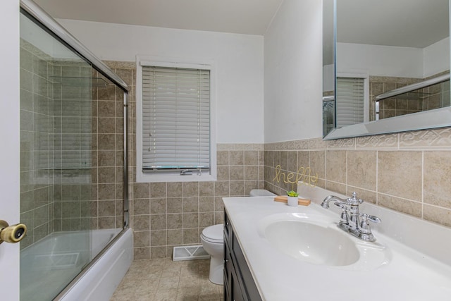854 Kings Cv, Princeton, IL 61356 - full bath with toilet, vanity, shower / bath combination with glass door, tile walls, and a wainscoted wall