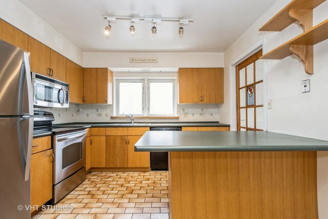 kitchen featuring decorative backsplash, appliances with stainless steel finishes, dark countertops, brown cabinets, and a sink