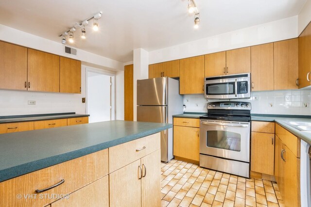 kitchen with track lighting, decorative backsplash, visible vents, and stainless steel appliances