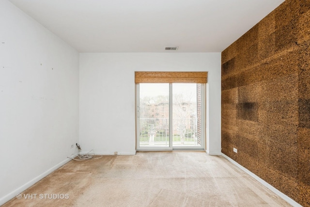 carpeted spare room featuring baseboards and visible vents