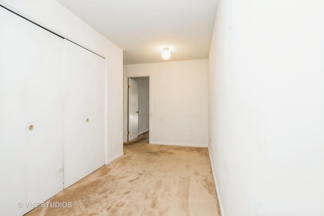 unfurnished bedroom with a closet and light carpet