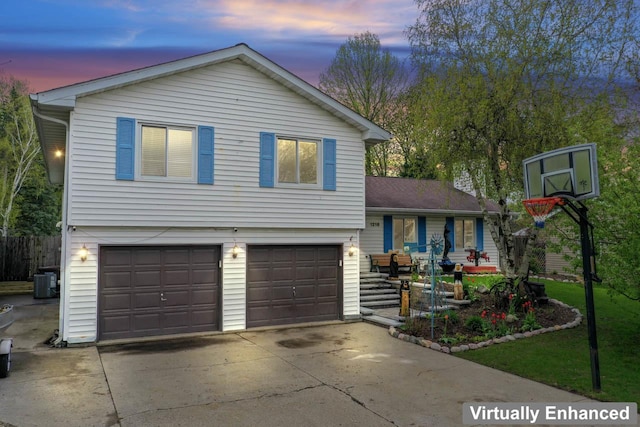 tri-level home with central AC unit, an attached garage, and concrete driveway