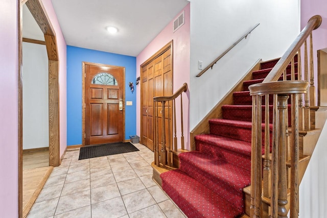 foyer featuring tile patterned floors, visible vents, baseboards, and stairway