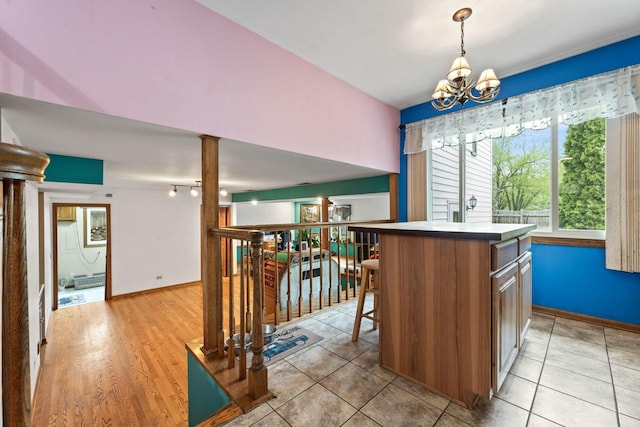 interior space featuring an inviting chandelier, baseboards, light tile patterned floors, and ornate columns