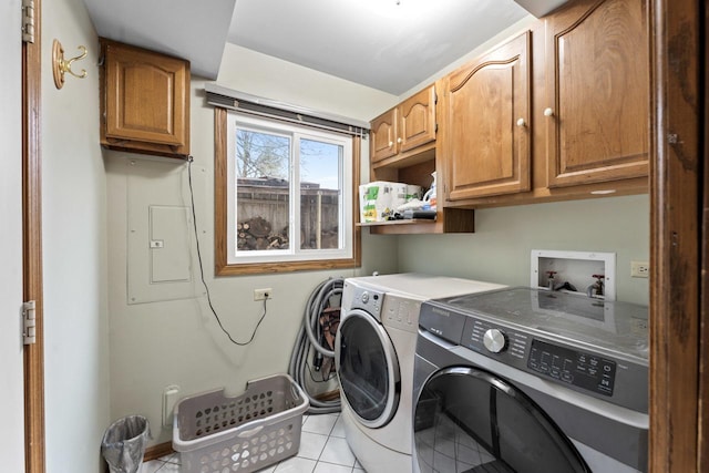 clothes washing area with cabinet space, electric panel, washing machine and dryer, and light tile patterned flooring