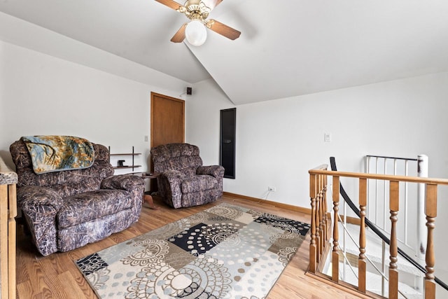 sitting room with ceiling fan, vaulted ceiling, wood finished floors, and an upstairs landing