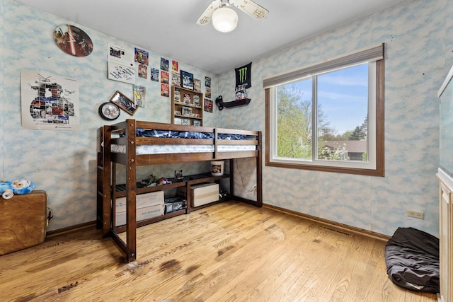 bedroom featuring wallpapered walls, baseboards, and hardwood / wood-style floors