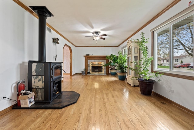 living area with ceiling fan, a wood stove, wood finished floors, and visible vents
