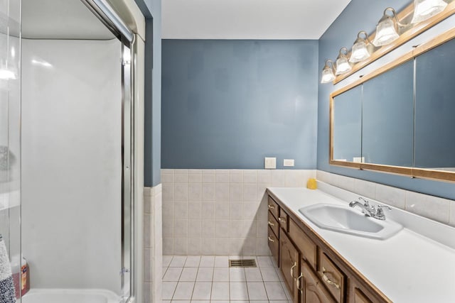 bathroom featuring visible vents, tile walls, vanity, tile patterned floors, and a shower with door