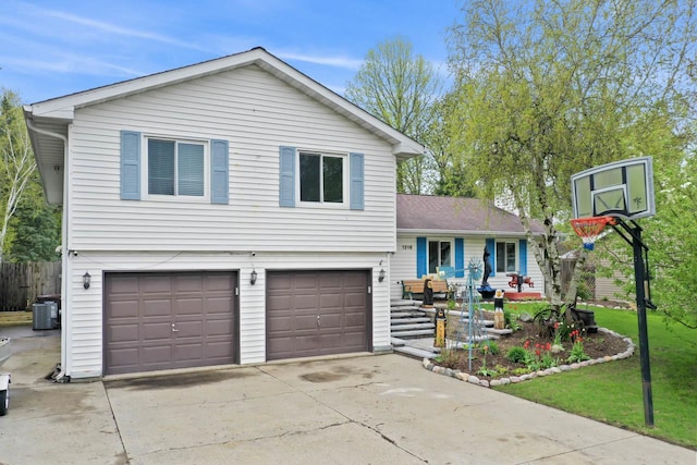 tri-level home featuring driveway, a front yard, central AC unit, a garage, and fence