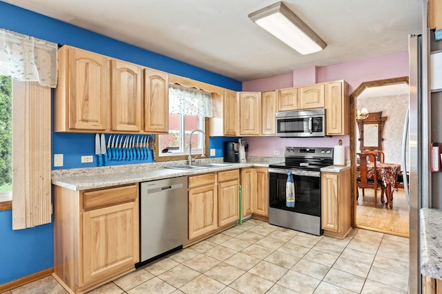 kitchen featuring light countertops, a sink, light brown cabinetry, and stainless steel appliances