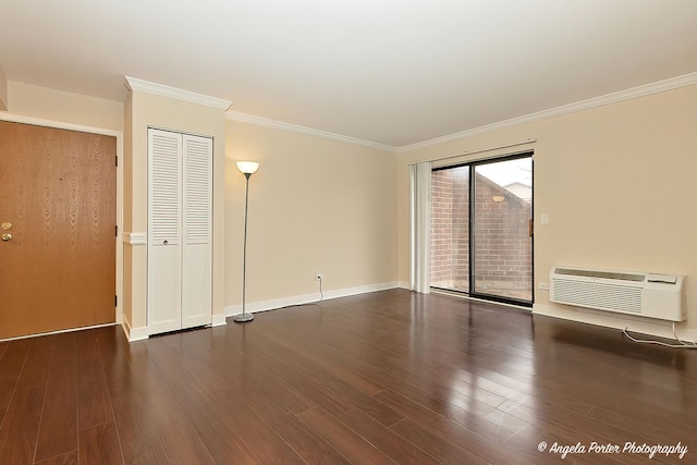 spare room with a wall mounted AC, wood finished floors, crown molding, and baseboards