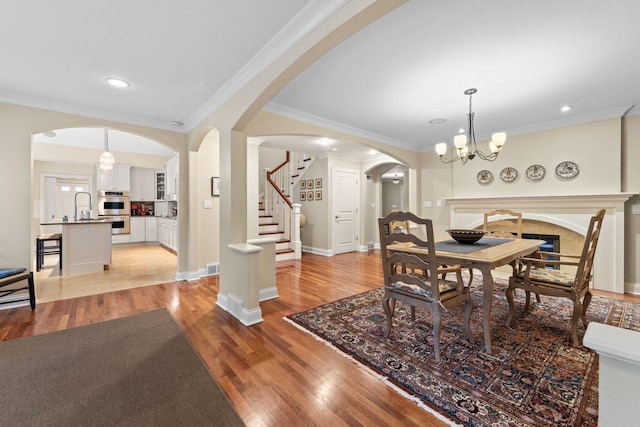 860 Kenton Rd, Deerfield, IL 60015 - dining area with arched walkways, light wood-style floors, ornamental molding, stairs, and a chandelier