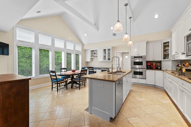 860 Kenton Rd, Deerfield, IL 60015 - kitchen featuring high vaulted ceiling, stainless steel appliances, light tile patterned floors, glass insert cabinets, and a kitchen island with sink