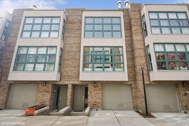 multi unit property with an attached garage, stucco siding, and brick siding