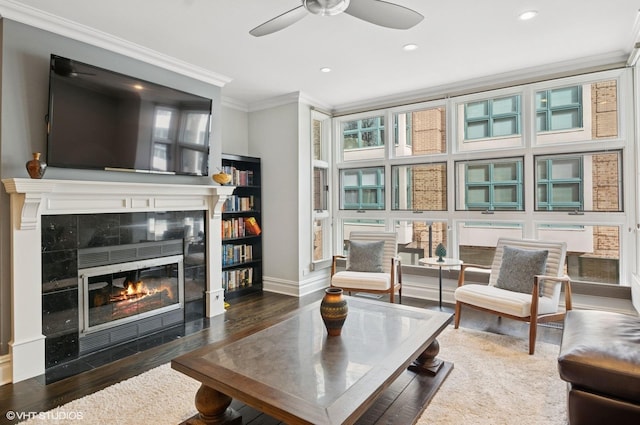 living room with a ceiling fan, wood finished floors, a fireplace, ornamental molding, and recessed lighting