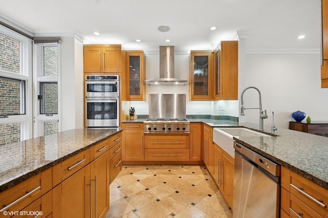 kitchen featuring wall chimney range hood, a sink, ornamental molding, and appliances with stainless steel finishes