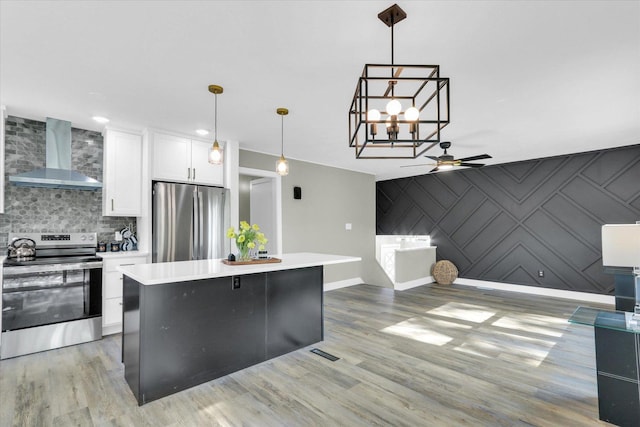1801 Cindy Lynn St, Urbana, IL 61802 - kitchen with stainless steel appliances, wall chimney range hood, an accent wall, a ceiling fan, and white cabinetry