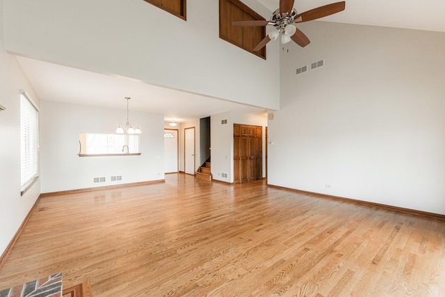 unfurnished living room featuring visible vents, light wood-style floors, baseboards, high vaulted ceiling, and ceiling fan with notable chandelier
