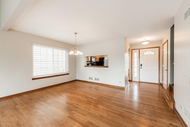 foyer entrance featuring light wood-style floors, baseboards, a notable chandelier, and visible vents