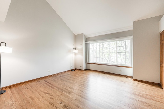 spare room with light wood-type flooring, baseboards, and high vaulted ceiling