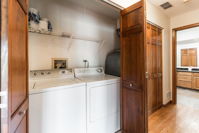 laundry area featuring laundry area, washer and clothes dryer, light wood-style floors, and visible vents