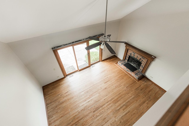 unfurnished living room featuring high vaulted ceiling, ceiling fan, a fireplace, and light wood-type flooring
