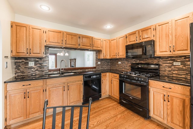 kitchen featuring decorative backsplash, recessed lighting, a sink, light wood-style flooring, and black appliances