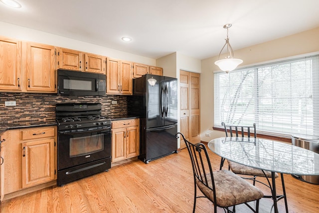 kitchen with dark countertops, light wood finished floors, tasteful backsplash, pendant lighting, and black appliances