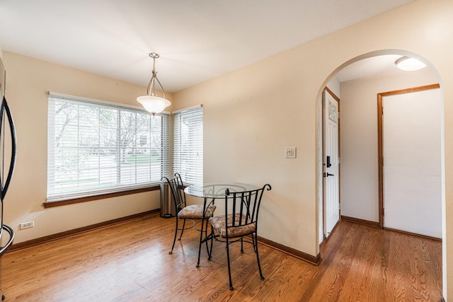 dining area featuring baseboards, arched walkways, and wood finished floors