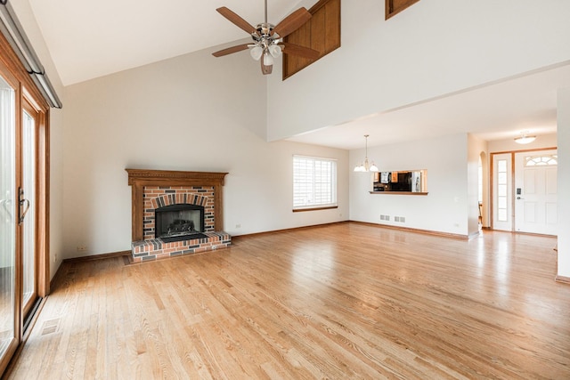 unfurnished living room featuring a high ceiling, a fireplace, light wood finished floors, and visible vents