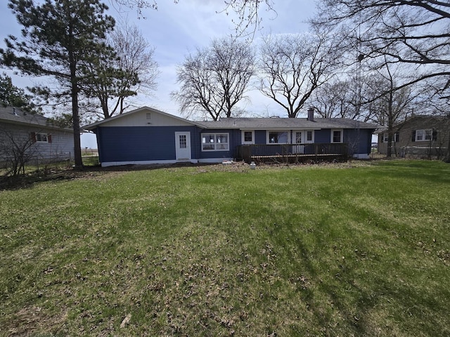ranch-style home with a chimney, a wooden deck, fence, and a front yard