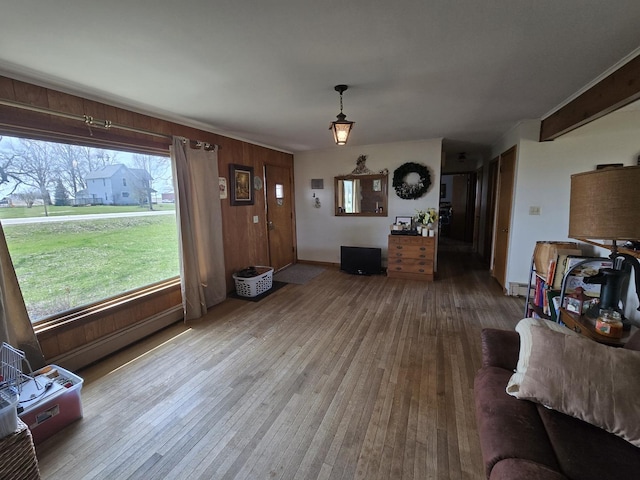 living room featuring a baseboard heating unit, hardwood / wood-style flooring, and wooden walls
