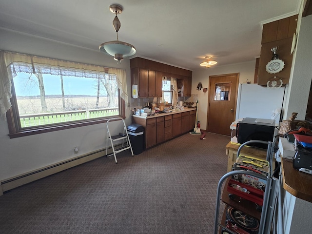 kitchen with a baseboard heating unit, dark colored carpet, freestanding refrigerator, and a sink