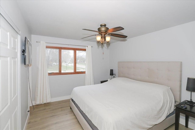 bedroom with baseboards, a ceiling fan, and light wood-type flooring