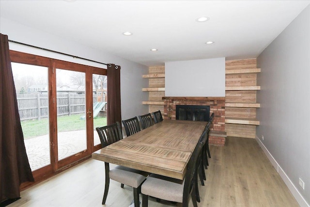 dining room featuring a brick fireplace, baseboards, recessed lighting, and light wood-style floors