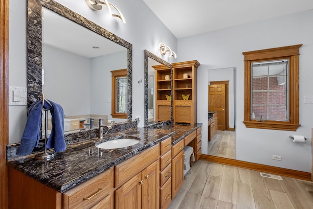 full bath with wood finished floors, vanity, and baseboards