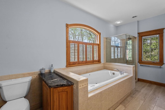 full bathroom featuring a stall shower, a bath, toilet, wood finished floors, and vanity
