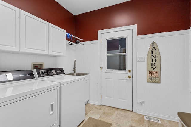 washroom featuring cabinet space, independent washer and dryer, and a wainscoted wall