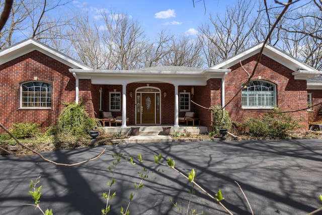 ranch-style home featuring brick siding and a porch