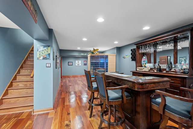 indoor dry bar with stairs, light wood-type flooring, and recessed lighting