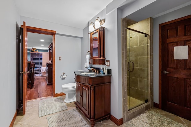 full bathroom featuring a shower stall, tile patterned floors, vanity, toilet, and baseboards