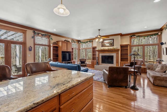 living area featuring a fireplace, ornamental molding, light wood-type flooring, a ceiling fan, and recessed lighting