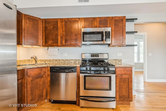 4449 W Sunnyside Ave Unit 2, Chicago, IL 60630 - kitchen featuring stainless steel appliances, light wood-style floors, and light stone counters