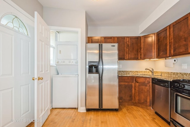 4449 W Sunnyside Ave Unit 2, Chicago, IL 60630 - kitchen with stainless steel appliances, stacked washer / drying machine, light stone countertops, and light wood-type flooring