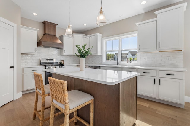 kitchen featuring a breakfast bar, a sink, white cabinetry, a kitchen island, and custom exhaust hood