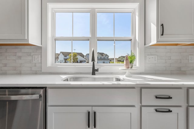 kitchen with a sink, light countertops, plenty of natural light, and stainless steel dishwasher